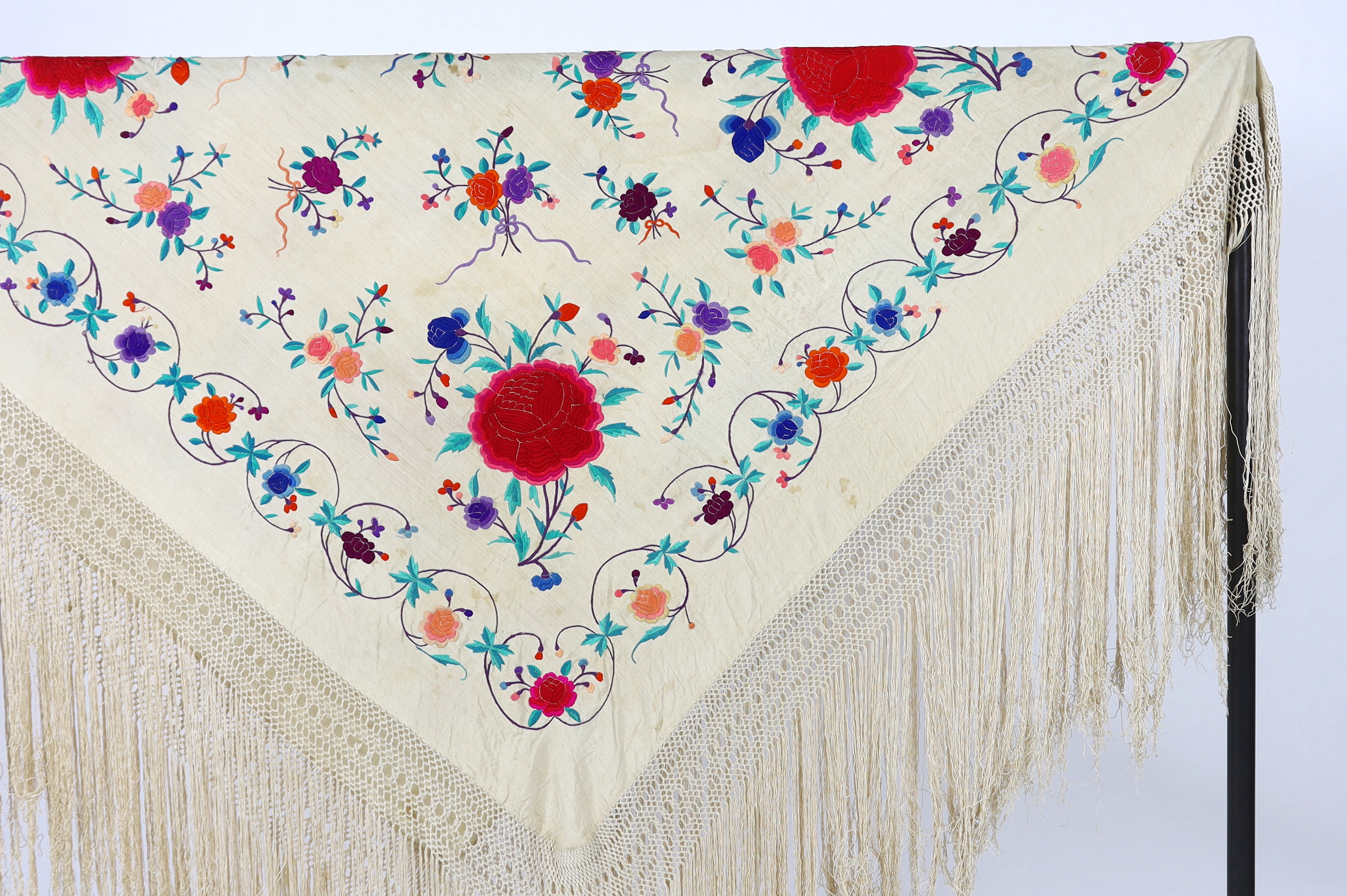 A late 19th / early 20th century cream silk fringed shawl, embroidered with all over polychrome silk floral motifs, 130 x 150cm not including fringe